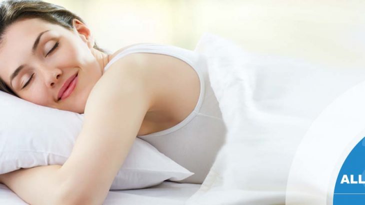Female in bed smiling with white covers