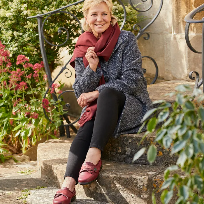 Woman sitting on steps in garden wearing winter clothing
